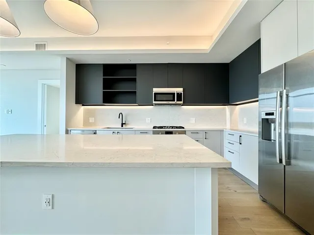 a view of kitchen with stainless steel appliances a sink and a refrigerator