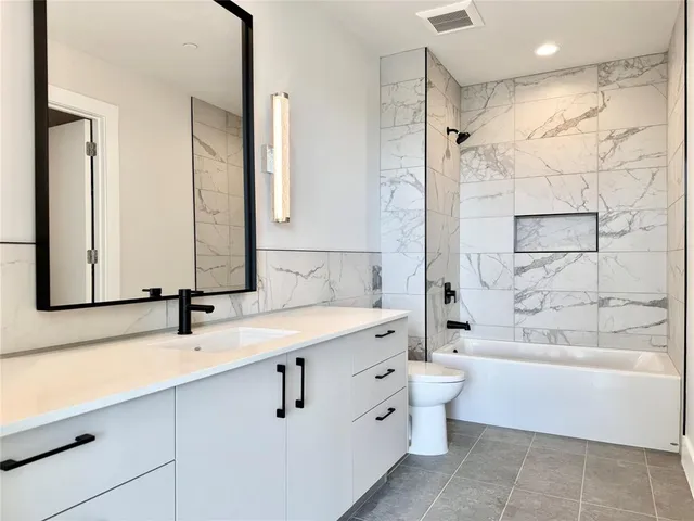 a bathroom with a bathtub shower sink mirror and toilet