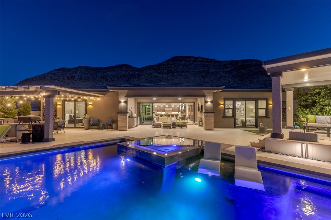 10118 Copper Edge Road Las Vegas, NV 89148 - Photo 30 of 48 An illuminated backyard oasis boasts a sparkling pool, integrated spa, and spacious patio under starry skies.