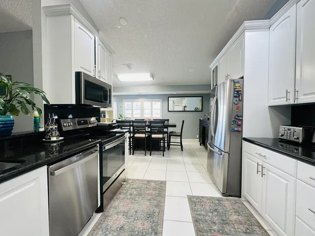 a kitchen with stainless steel appliances kitchen island granite countertop a refrigerator and a stove top oven