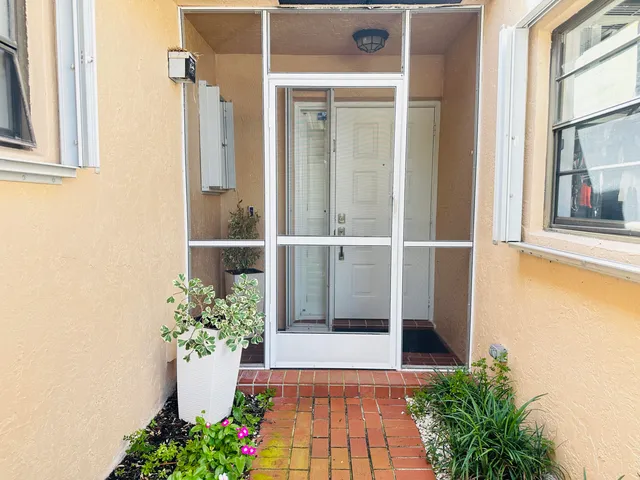 a view of a entryway door of the house with flower pots