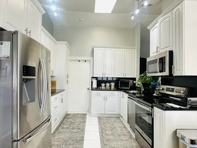 a kitchen with white cabinets and refrigerator
