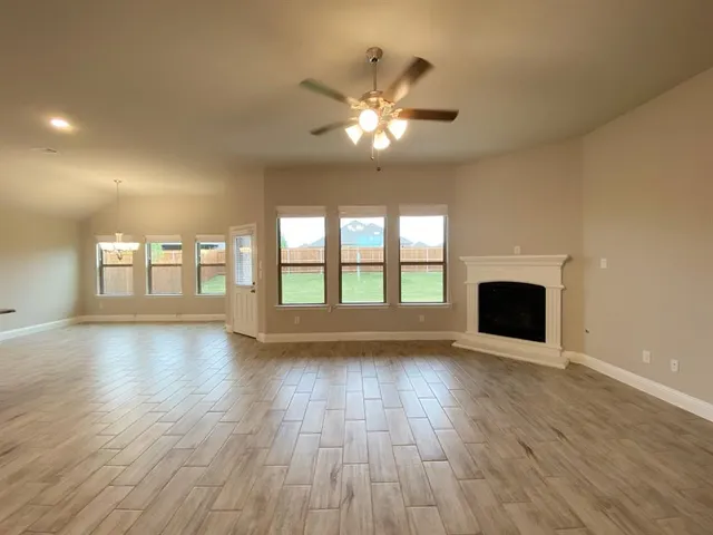 a view of an empty room with wooden floor and a fireplace
