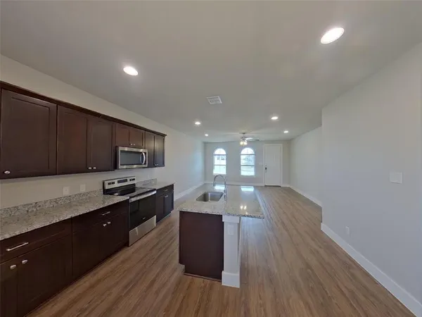 a kitchen with stainless steel appliances granite countertop a sink a stove and wooden floor
