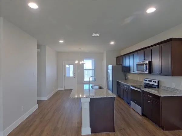 a large kitchen with stainless steel appliances a large counter top a stove and a wooden floors