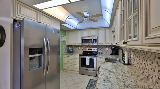 a kitchen with stainless steel appliances granite countertop a refrigerator a stove and a sink with wooden floor