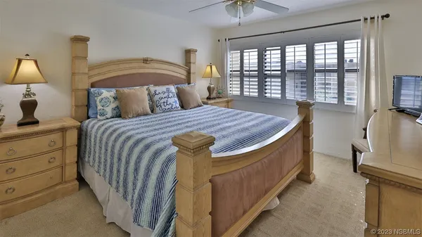 a bedroom with a bed a lamp and a flat tv screen next to a large window