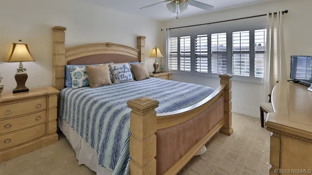 a bedroom with a bed a lamp and a flat tv screen next to a large window