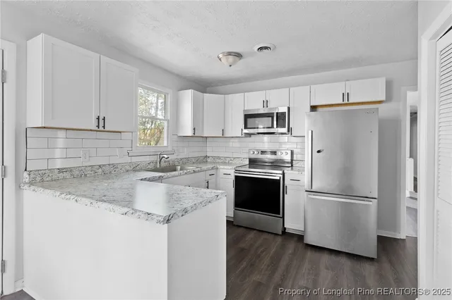 a kitchen with kitchen island granite countertop a refrigerator stove top oven and sink with wooden floor