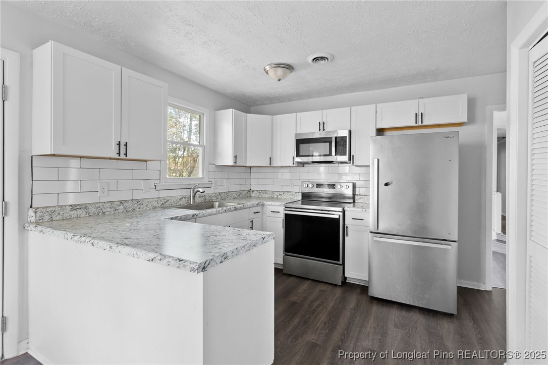 6838 Timbercroft Lane Fayetteville, NC 28314 - Photo 7 of 17 a kitchen with kitchen island granite countertop a refrigerator stove top oven and sink with wooden floor