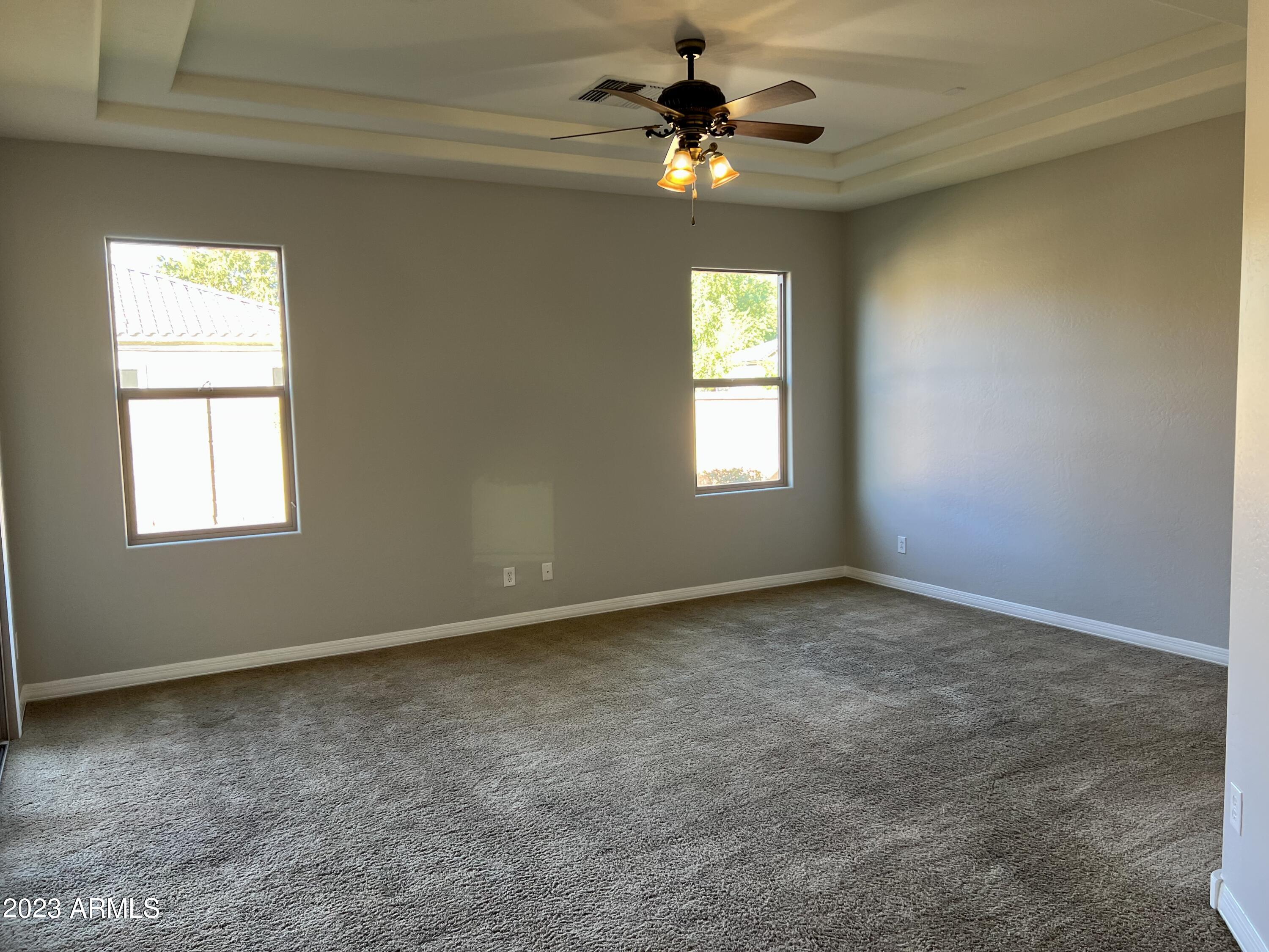 20296 East Sonoqui Boulevard Queen Creek, AZ 85142 - Photo 13 of 22 an empty room with windows and chandelier fan
