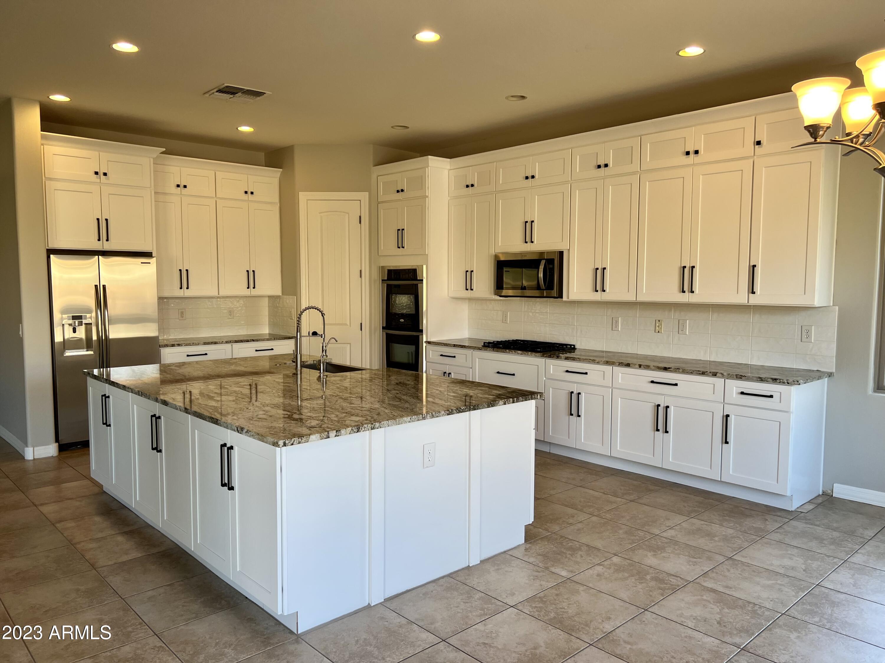 20296 East Sonoqui Boulevard Queen Creek, AZ 85142 - Photo 4 of 22 a kitchen with stainless steel appliances granite countertop a stove a sink and a refrigerator