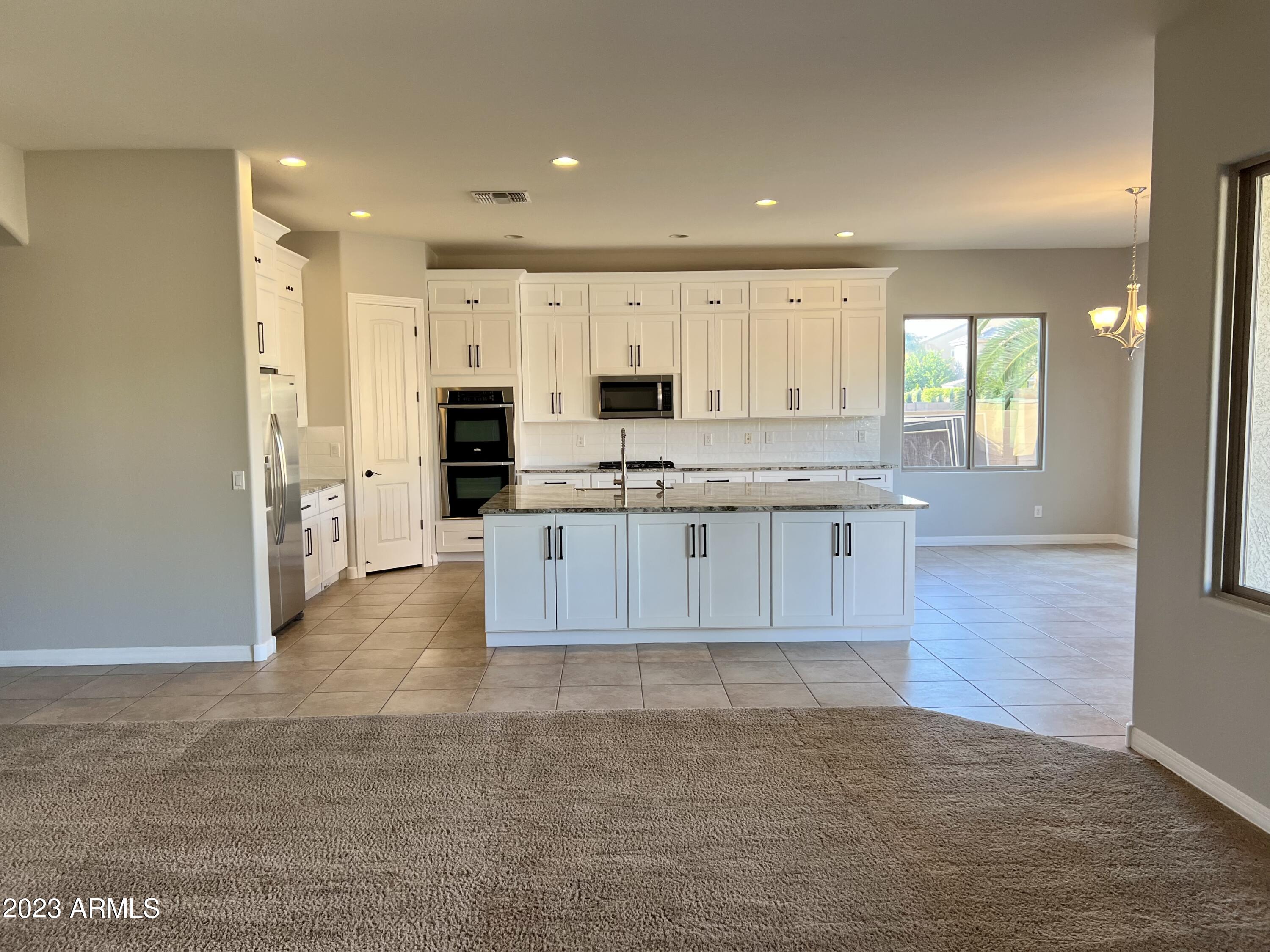 20296 East Sonoqui Boulevard Queen Creek, AZ 85142 - Photo 5 of 22 a large kitchen with cabinets and wooden floor