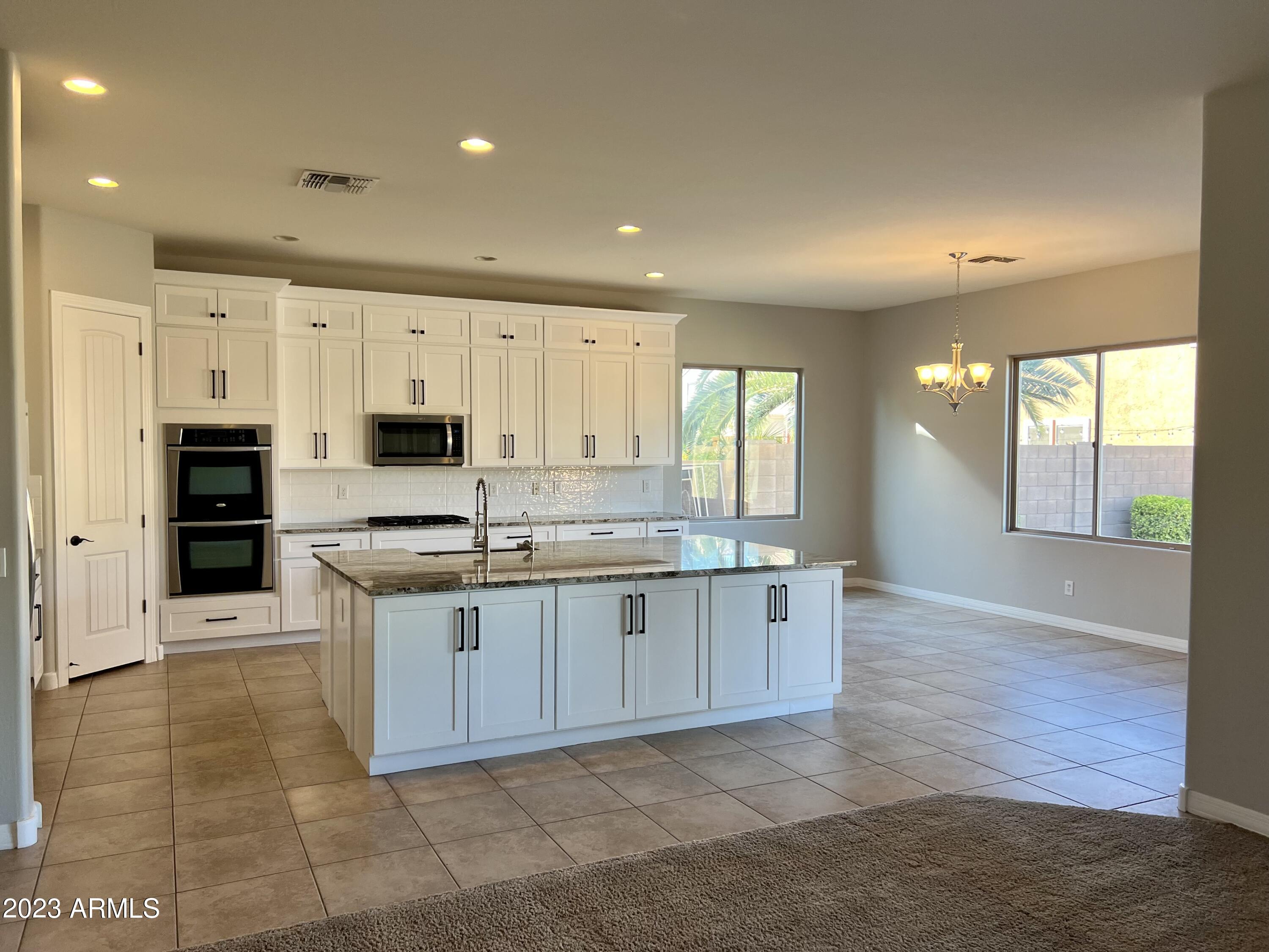 20296 East Sonoqui Boulevard Queen Creek, AZ 85142 - Photo 8 of 22 a large kitchen with stainless steel appliances granite countertop a stove a sink and a refrigerator