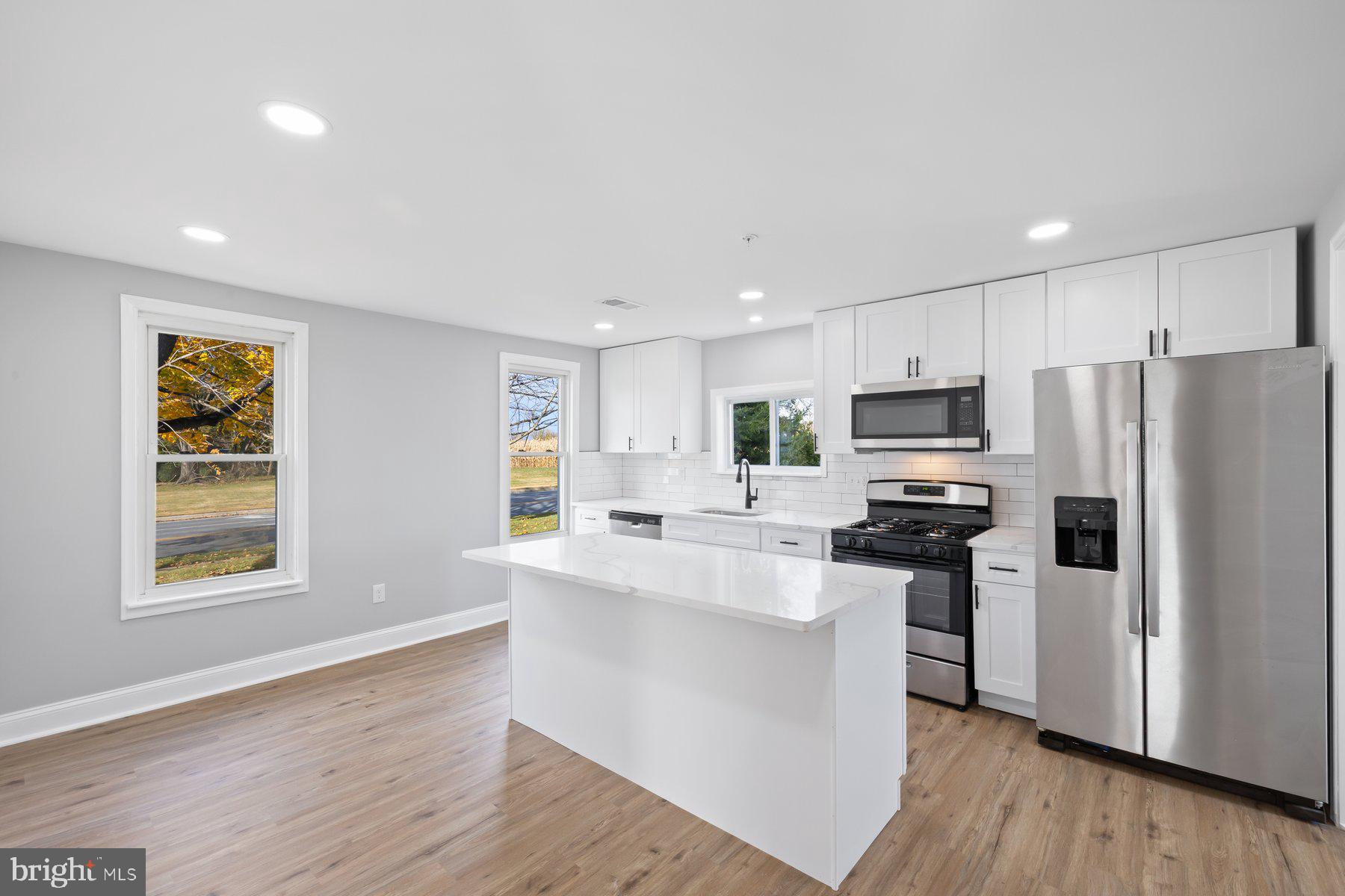 1809 Hanover Pike Hampstead, MD 21074 - Photo 5 of 53 a kitchen with stainless steel appliances a refrigerator a stove a sink and white cabinets with wooden floor