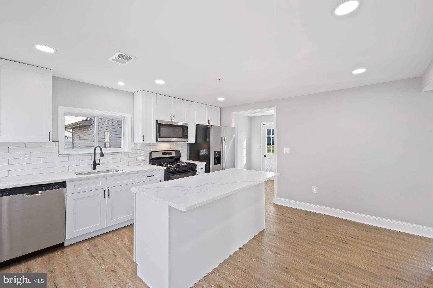 1809 Hanover Pike Hampstead, MD 21074 - Photo 6 of 53 a large white kitchen with wooden floor and stainless steel appliances