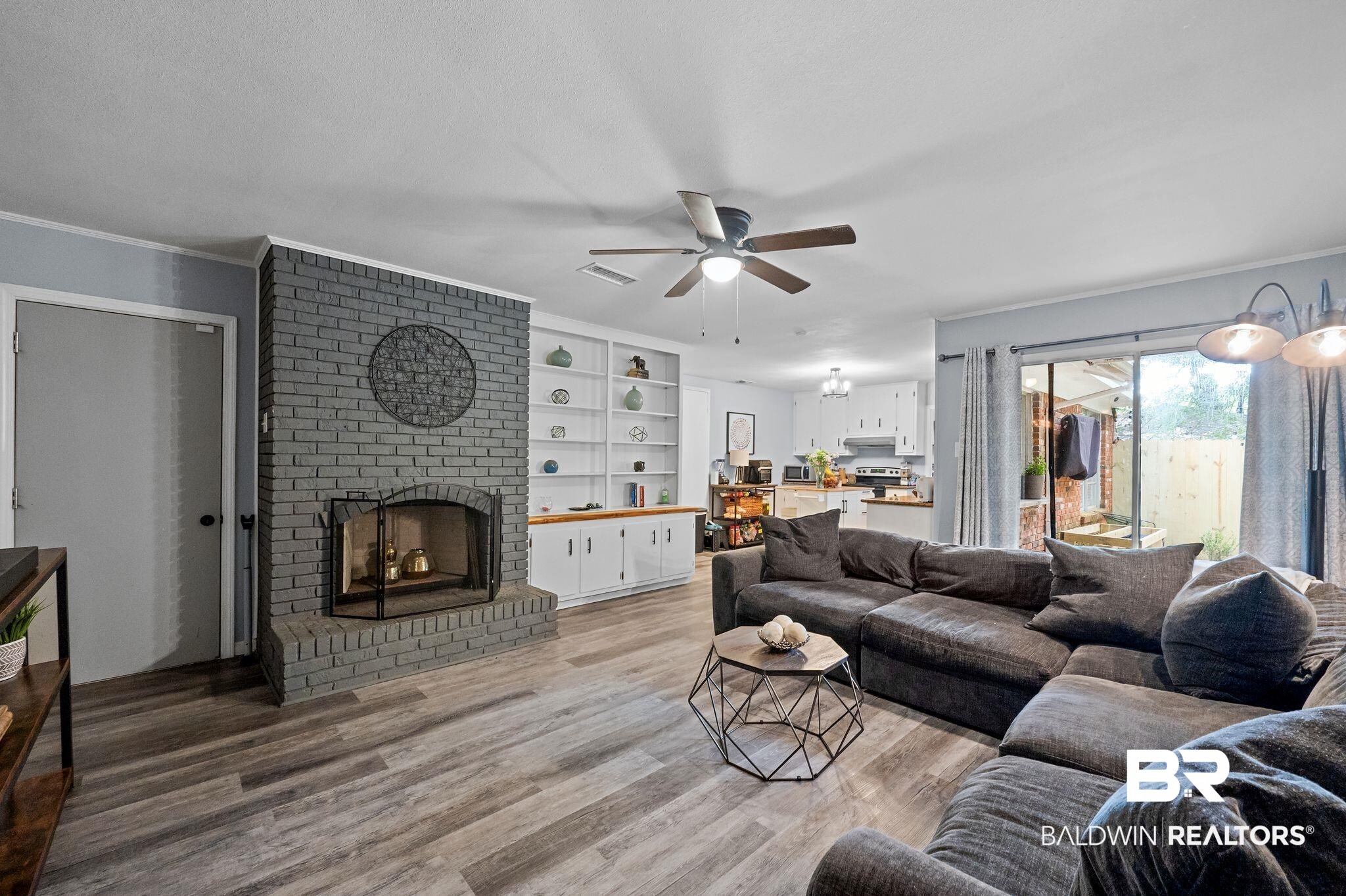 4724 Wicker Way Mobile, AL 36609 - Photo 17 of 36 Living area featuring a gray brick fireplace with a metal screen, wood-finish flooring, and a ceiling fan