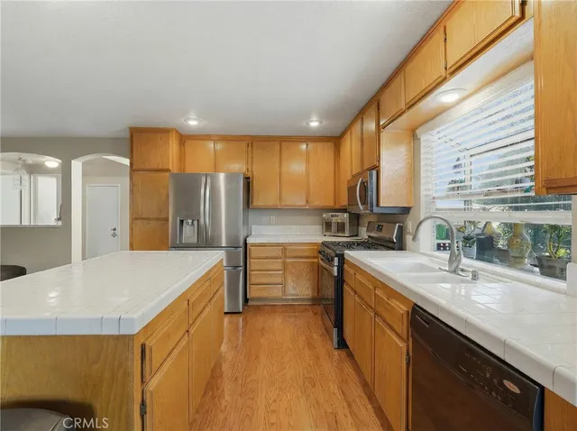 a large kitchen with stainless steel appliances granite countertop a sink a stove and refrigerator