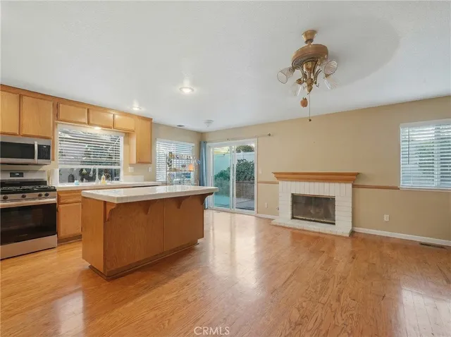 a large kitchen with stainless steel appliances granite countertop a stove top oven a sink dishwasher and a fireplace with wooden floor