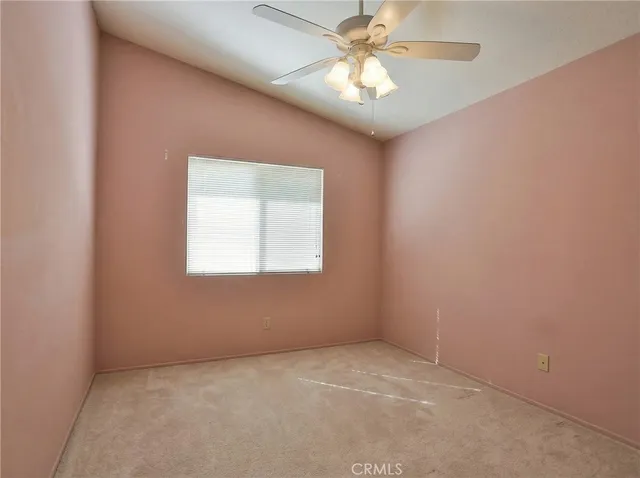 an empty room with a chandelier fan and windows