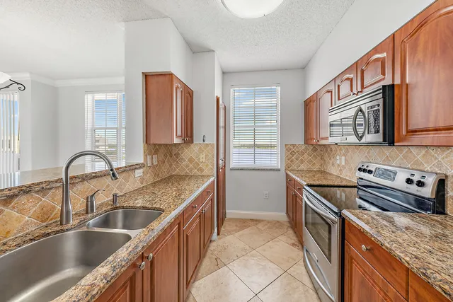 a kitchen with granite countertop a sink and a refrigerator