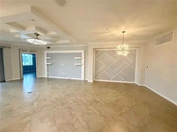 a view of an empty room and chandelier fan