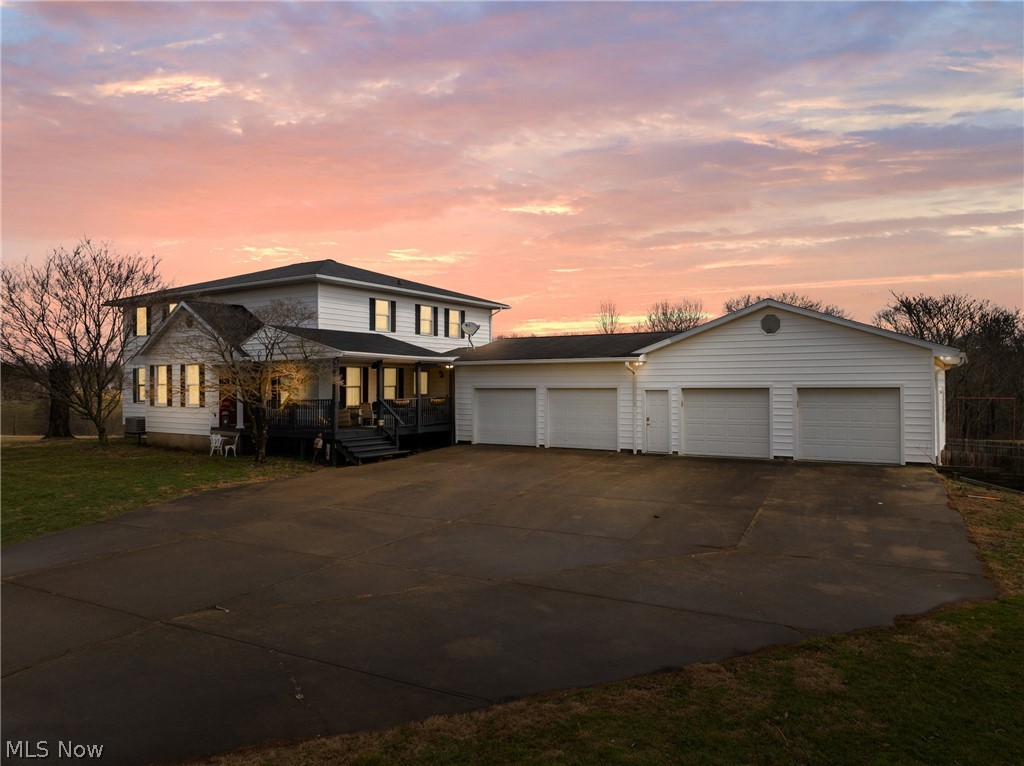 View of front of property featuring driveway, a garage, and a porch