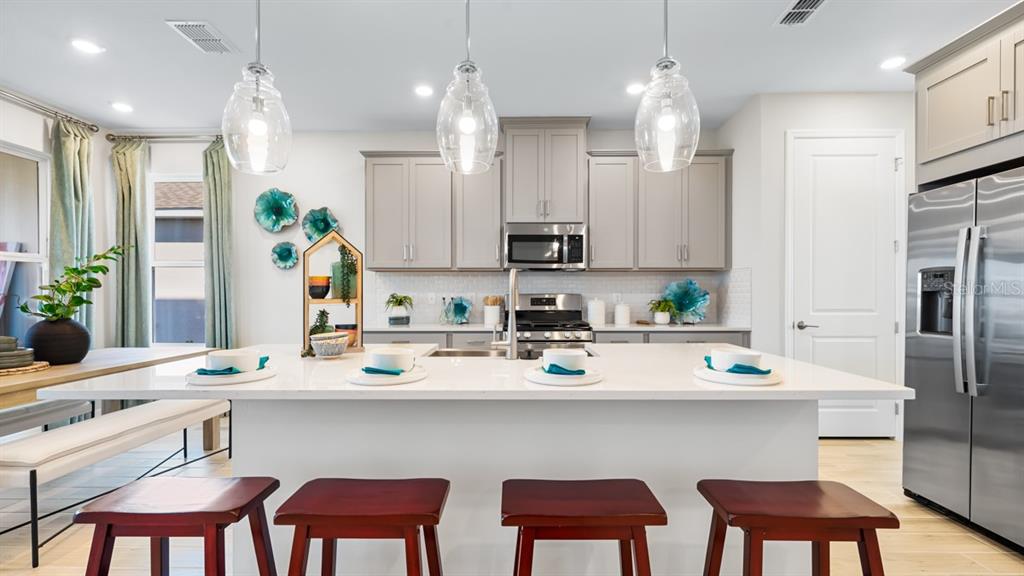 13333 Stable Place Parrish, FL 34219 - Photo 17 of 33 a kitchen with stainless steel appliances a dining table chairs refrigerator and sink
