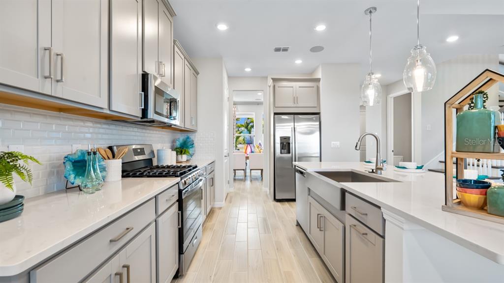 13333 Stable Place Parrish, FL 34219 - Photo 20 of 33 a kitchen with stainless steel appliances granite countertop a sink a stove top oven a refrigerator a counter space and cabinets