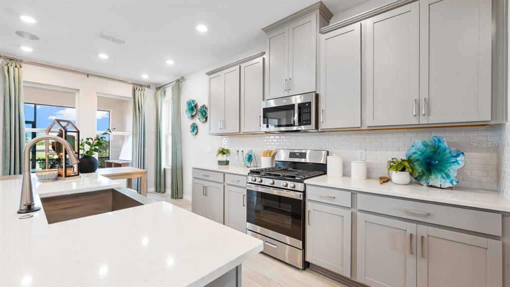 13333 Stable Place Parrish, FL 34219 - Photo 22 of 33 a kitchen with stainless steel appliances kitchen island granite countertop a stove a sink and a refrigerator