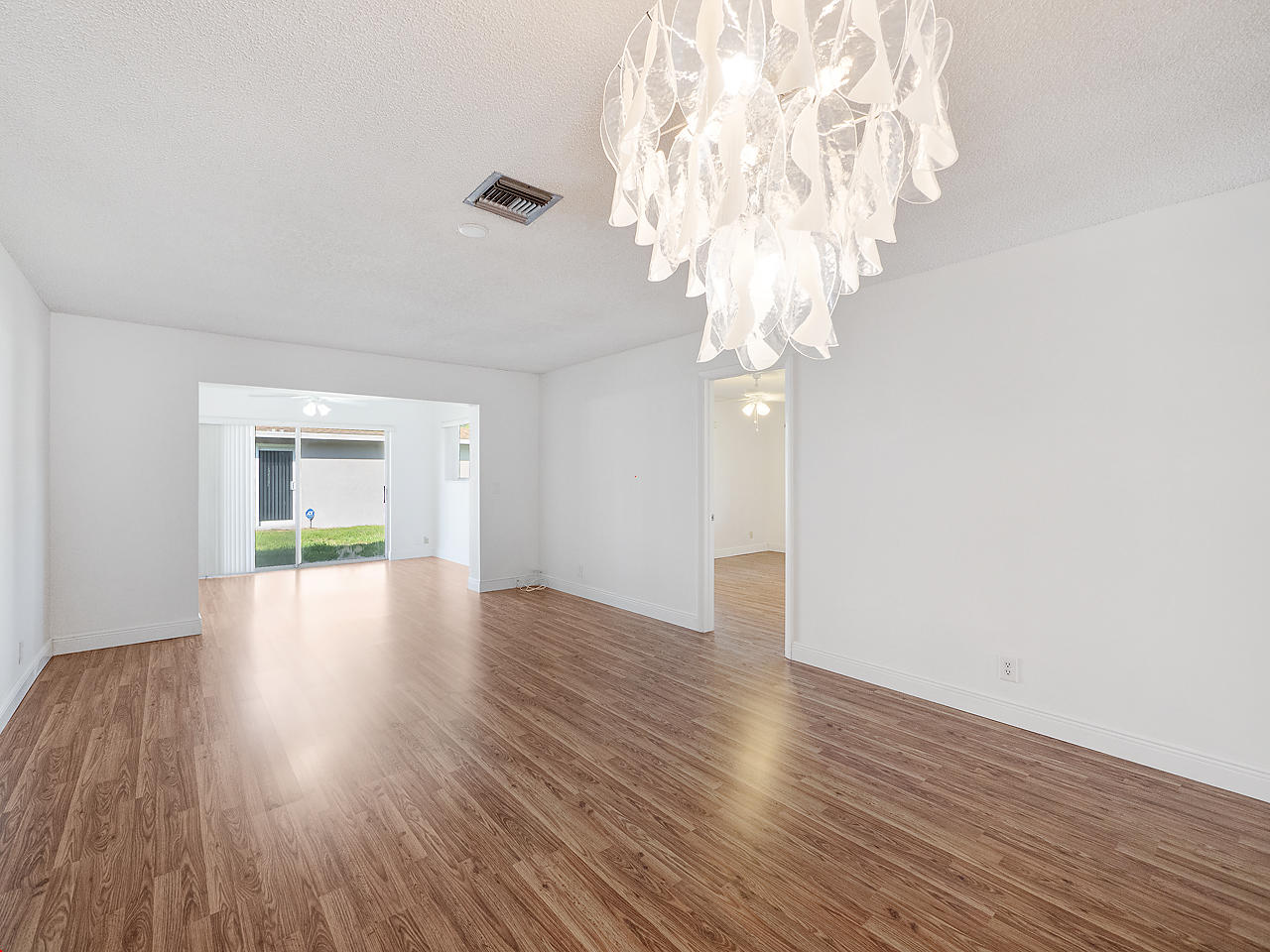 6723 Moonlit Drive Delray Beach, FL 33446 - Photo 6 of 16 a view of an empty room with wooden floor and a chandelier