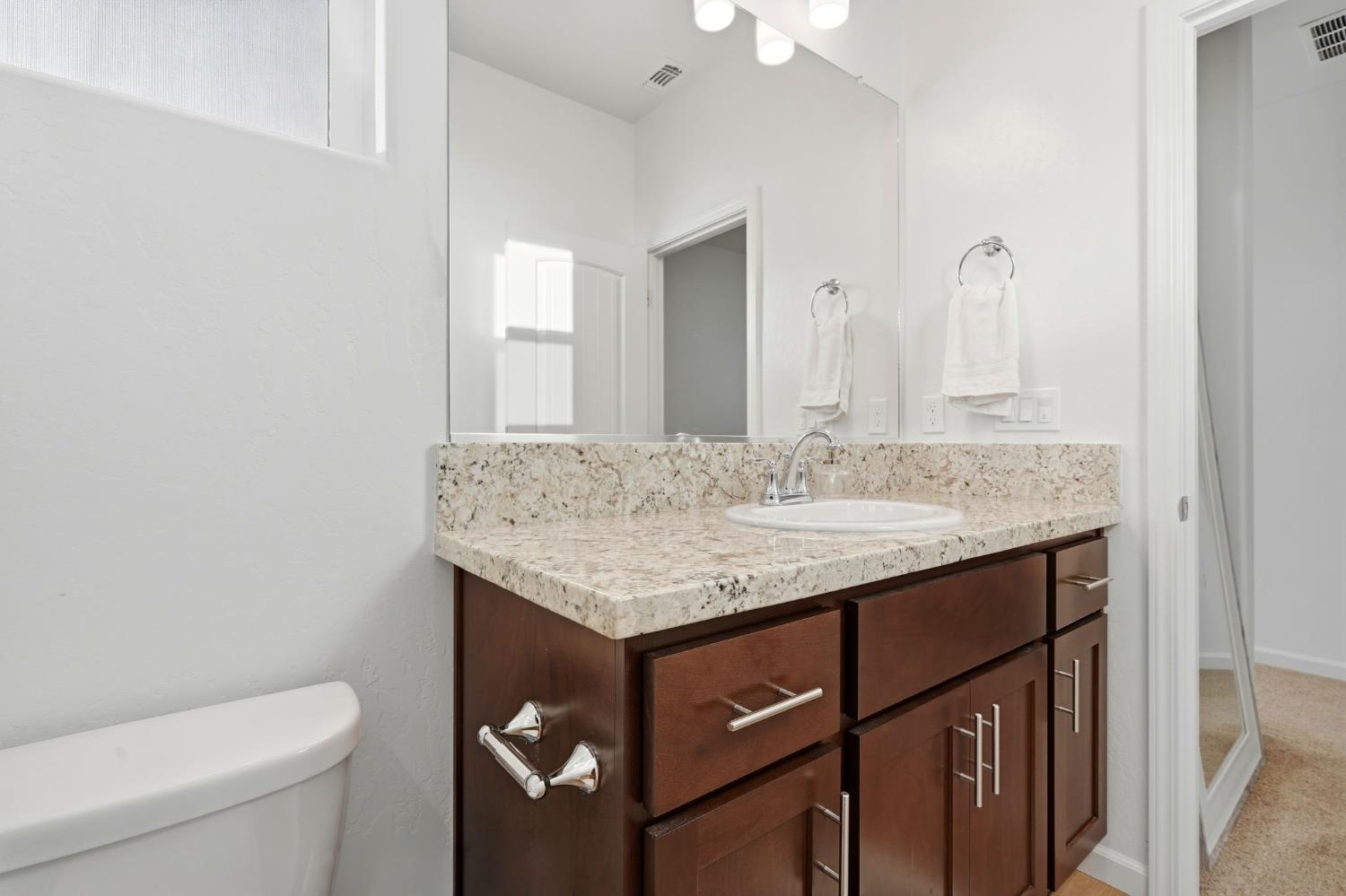 2566 Muscat Court Hanford, CA 93230 - Photo 37 of 55 a bathroom with a granite countertop sink a toilet and a mirror