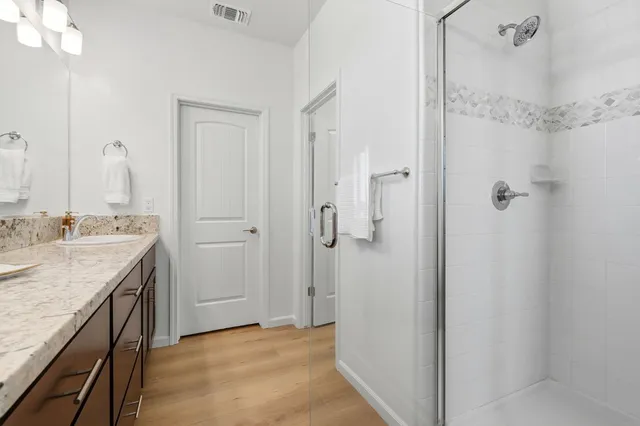 a bathroom with a granite countertop sink two mirror and shower
