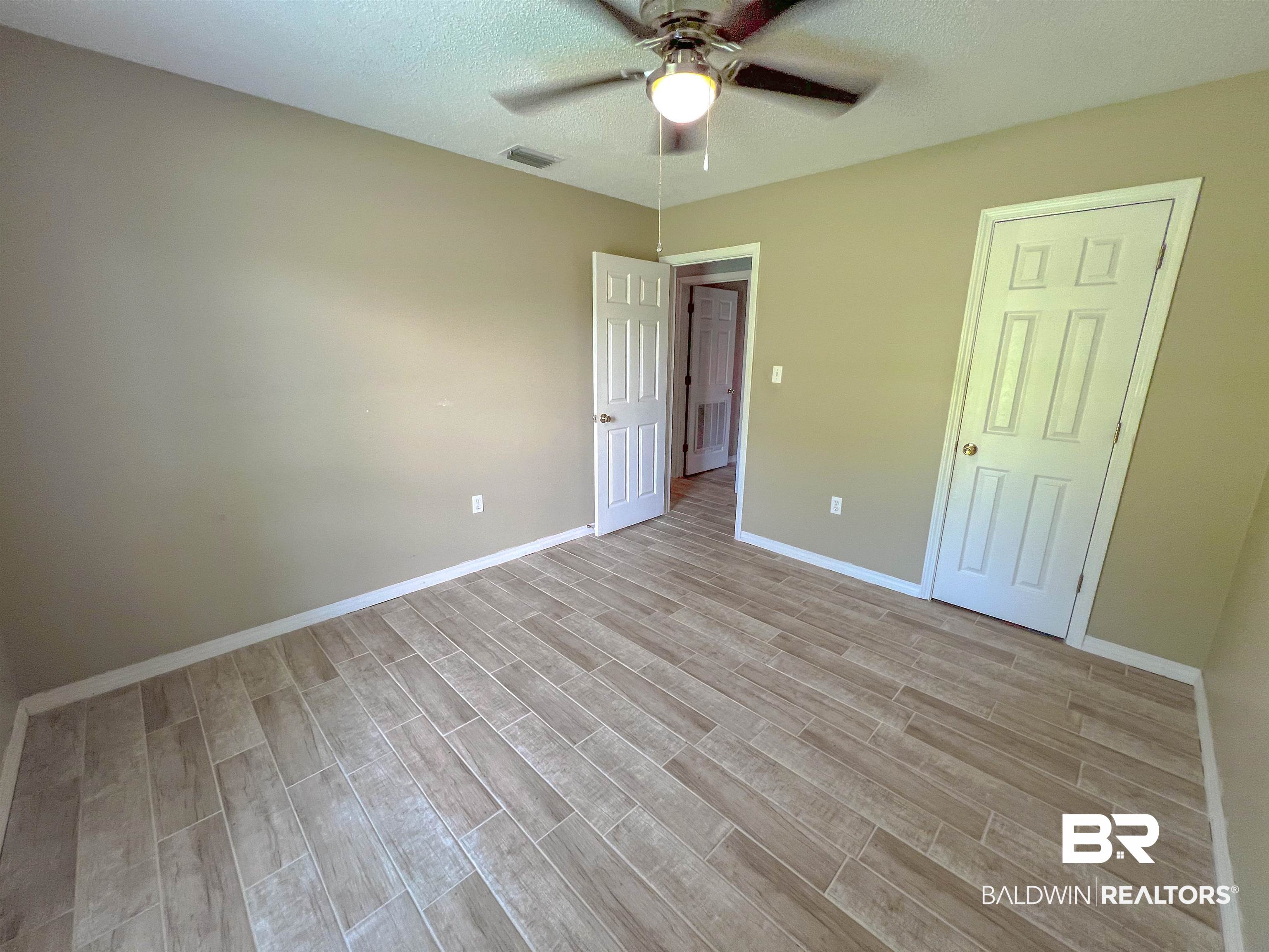 1200 South Juniper Street Foley, AL 36535 - Photo 15 of 23 Unfurnished bedroom featuring a textured ceiling, light wood-type flooring, and ceiling fan