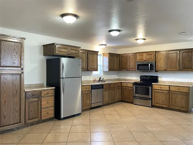 a kitchen with granite countertop a refrigerator and a stove top oven
