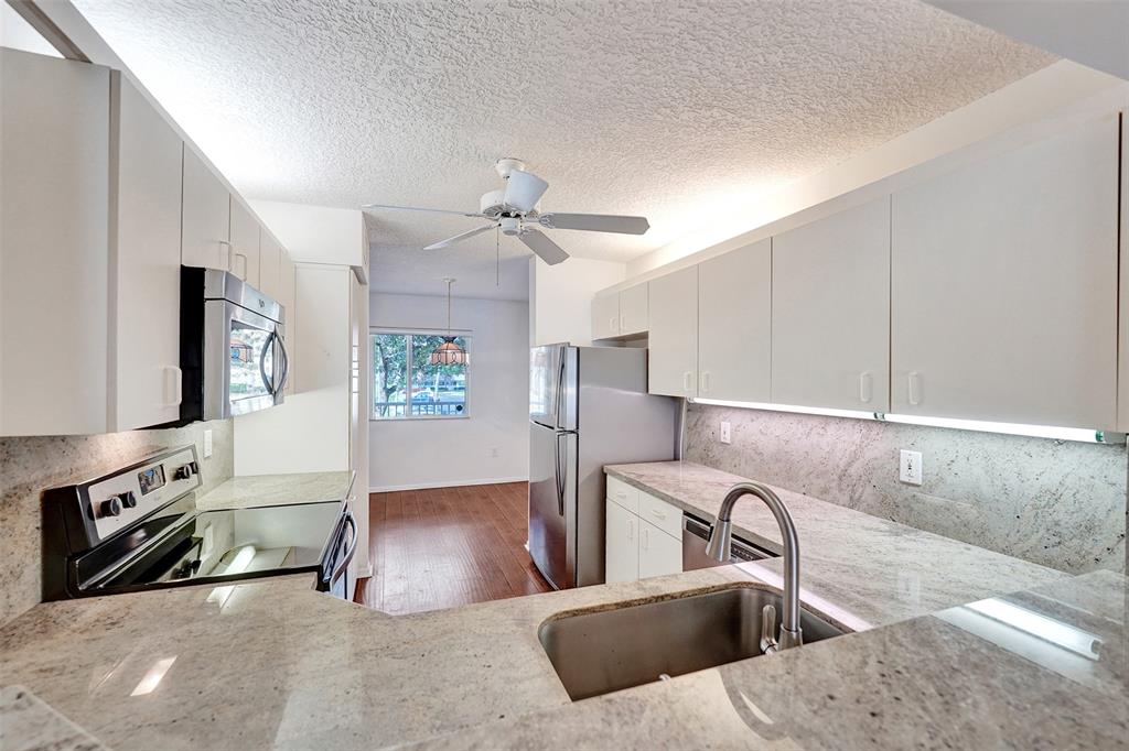 9563 Weldon Circle, Unit D212 Tamarac, FL 33321 - Photo 16 of 69 a kitchen with stainless steel appliances granite countertop a sink a stove and a refrigerator