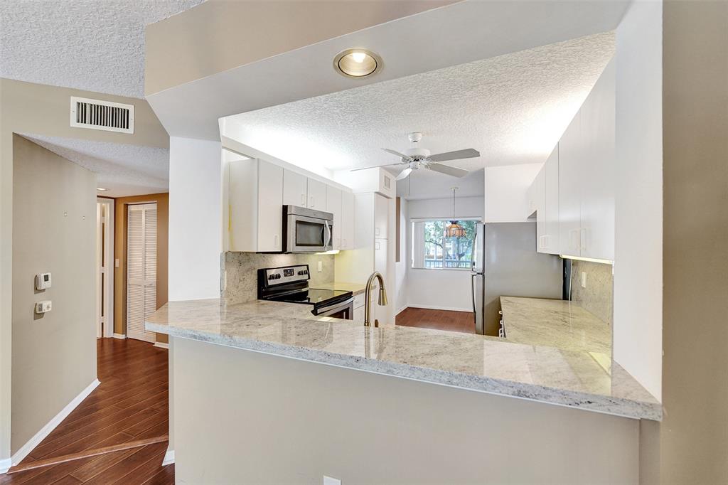 9563 Weldon Circle, Unit D212 Tamarac, FL 33321 - Photo 17 of 69 a large kitchen with a lot of counter space and wooden floor