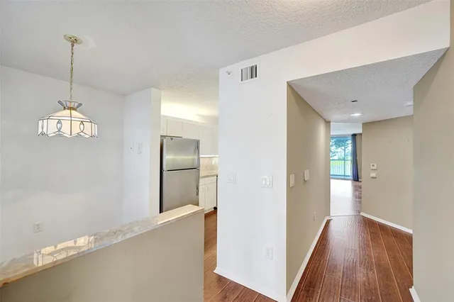 a view of a room with wooden floor a ceiling fan and windows