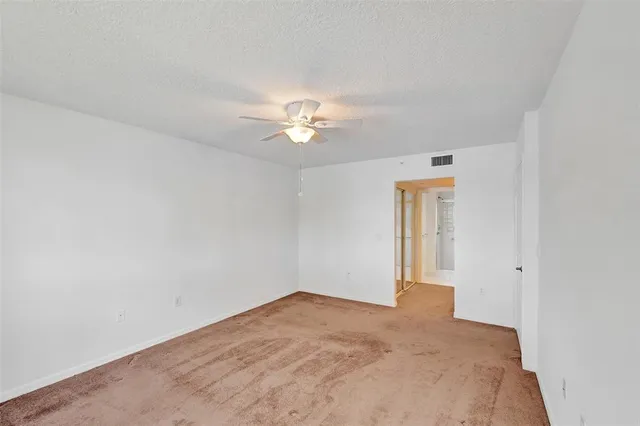 an empty room with a window and ceiling fan