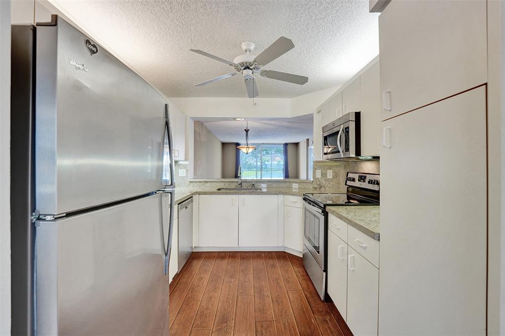 9563 Weldon Circle, Unit D212 Tamarac, FL 33321 - Photo 9 of 69 a kitchen with white cabinets and white appliances