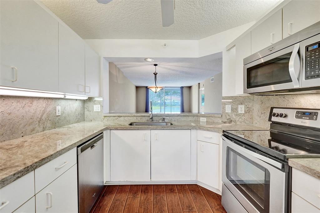 9563 Weldon Circle, Unit D212 Tamarac, FL 33321 - Photo 10 of 69 a kitchen with stainless steel appliances granite countertop a sink and microwave