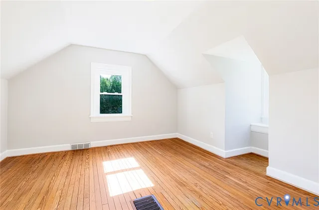 a view of empty room with wooden floor fireplace and a window