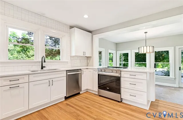 a kitchen with stainless steel appliances white cabinets and wooden floor