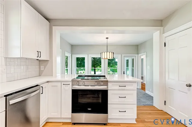 a kitchen with kitchen island granite countertop a stove a sink and a chandelier
