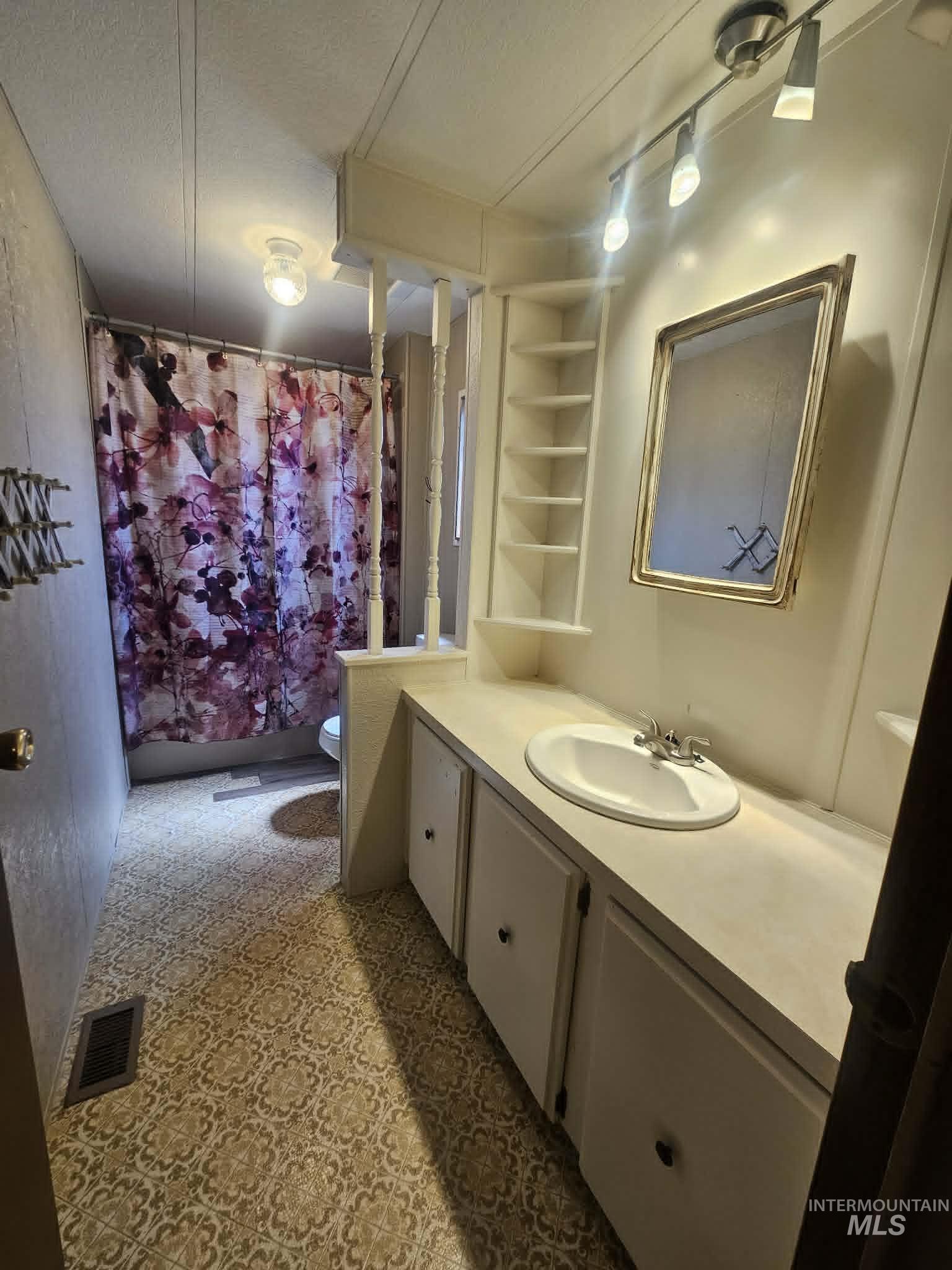 461 Greenleaf Street Boise, ID 83713 - Photo 3 of 19 Bathroom featuring a single vanity, built-in shelving, patterned flooring, a track light fixture, and a shower/tub combination