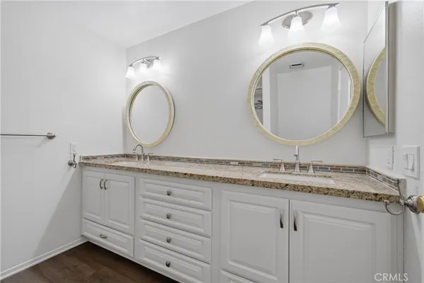 a bathroom with a granite countertop double vanity sink and a mirror