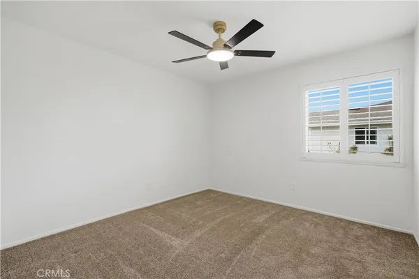 an empty room with ceiling fan and windows