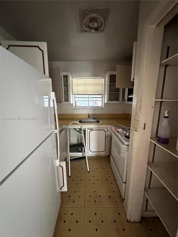 a kitchen with a sink a stove a refrigerator and furniture