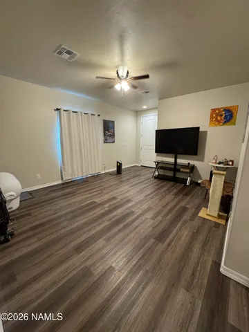 a view of a room with wooden floor and a ceiling fan