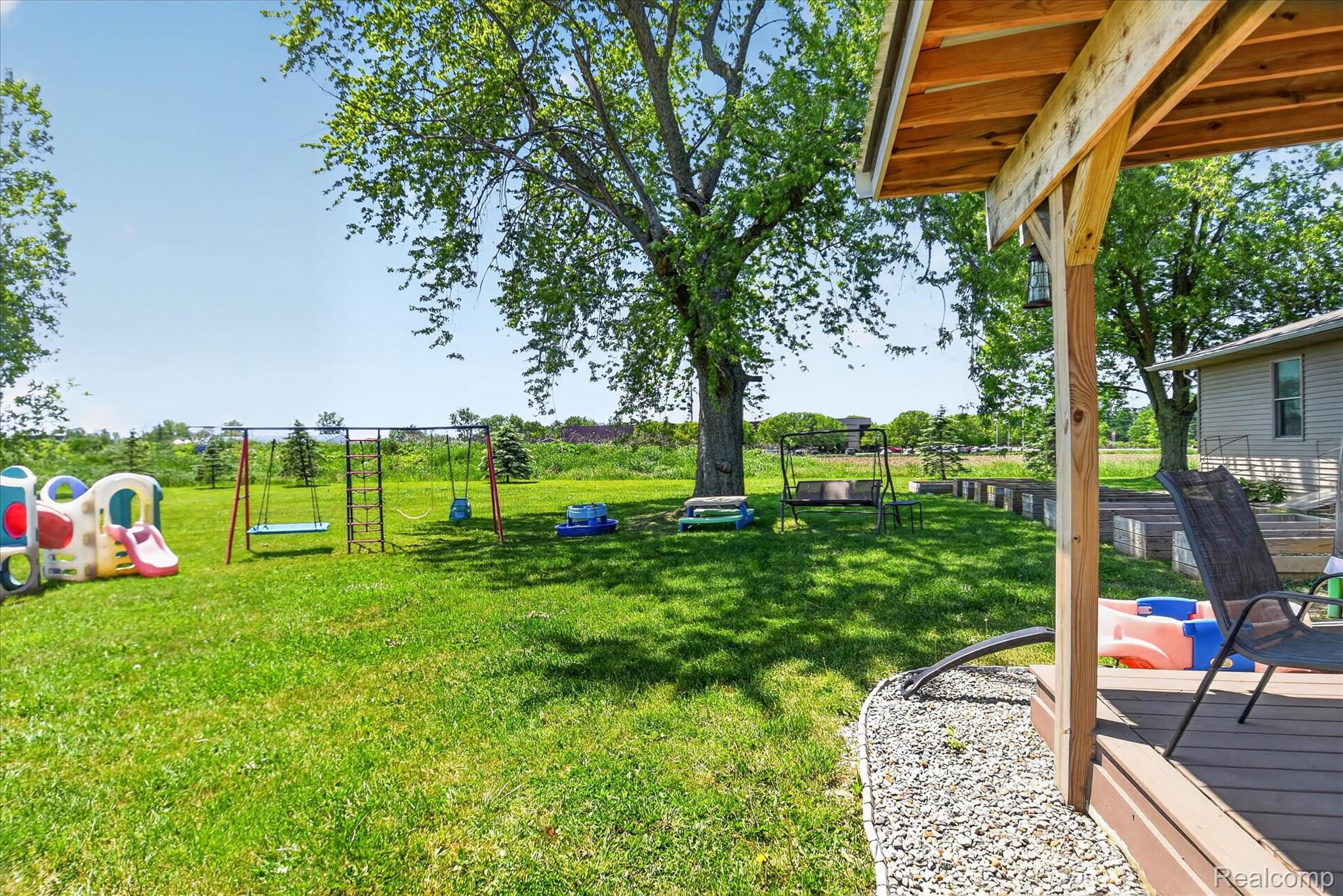 3949 West Burns Line Road Brown City, MI 48416 - Photo 63 of 70 Expansive backyard featuring a manicured lawn, mature shade trees, and a wooden deck with an overhead cover